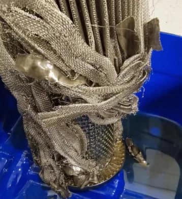Ruptured oil filter element with the mesh loose from its bottom fixation plate