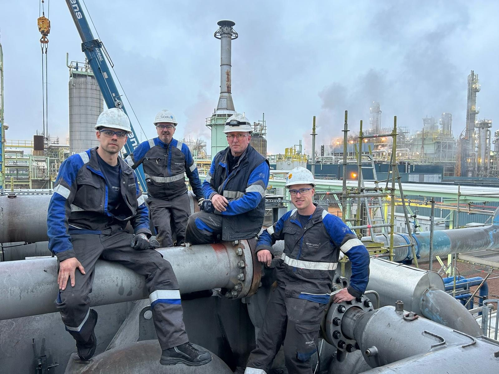 Energetic Machinery field service technicians on site at a petrochemical plant, standing on rotating equipment piping